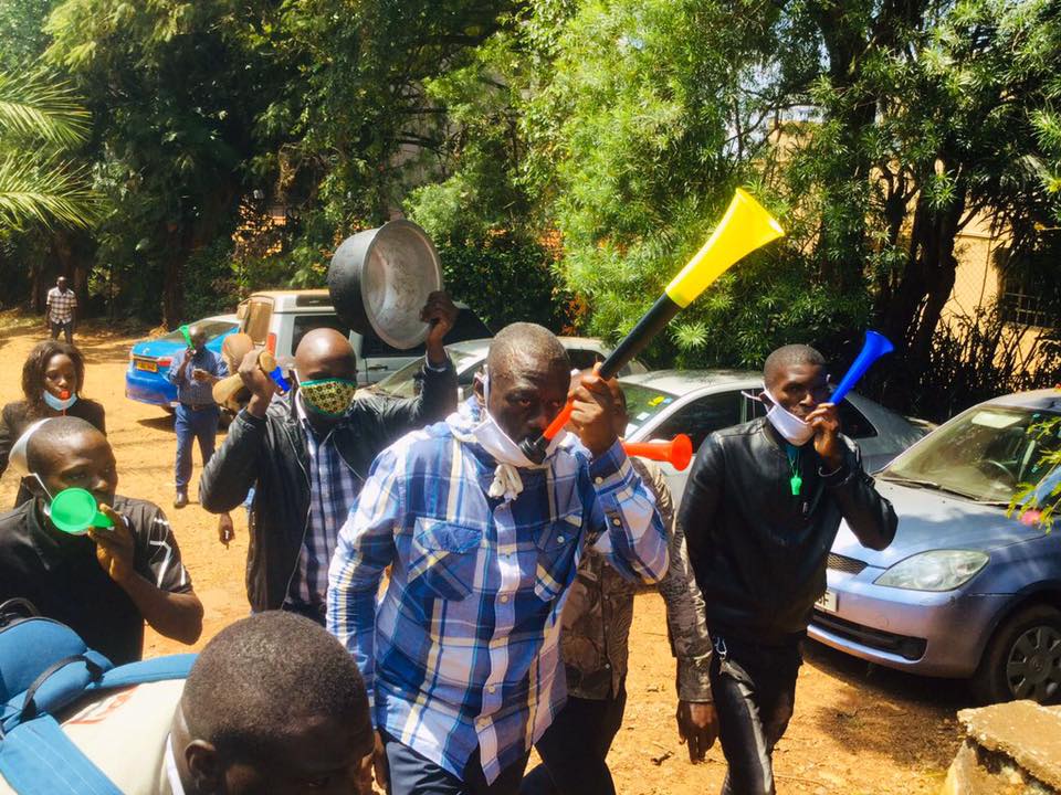 Dr Besigye blowing a vuvuzela at his office on Katonga Road in Kampala in the spirit of the No Nedda campaign after a coalition deal with Bobi Wine and other political players.