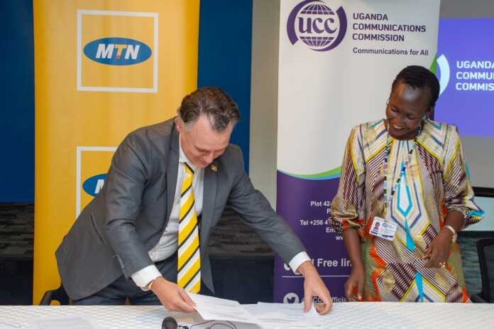 MTN Uganda CEO Wim Vanhellpute scans through documents as UCC ED Irene Kaggwa Ssewankambo looks on. Uganda Communications Commission (UCC) has officially granted MTN Uganda a 12-year license but set terms and conditions
