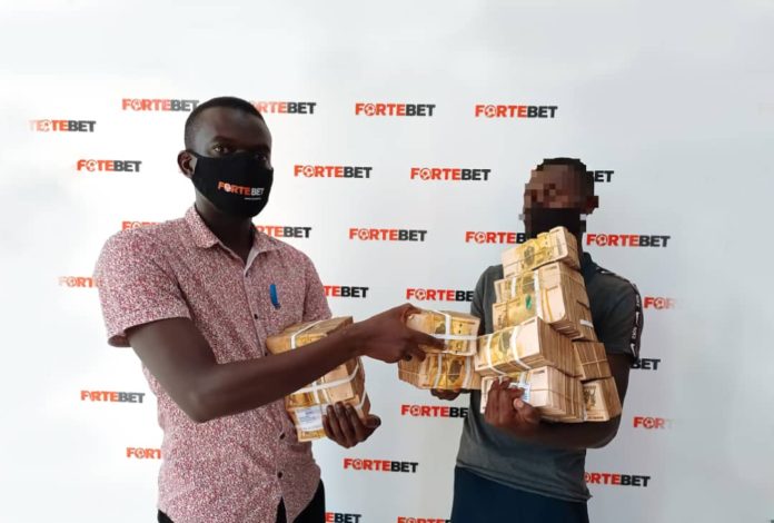A Fortebet official handing the prize money to the winner at their Kampala head offices on Wednesday, December 09, 2020.